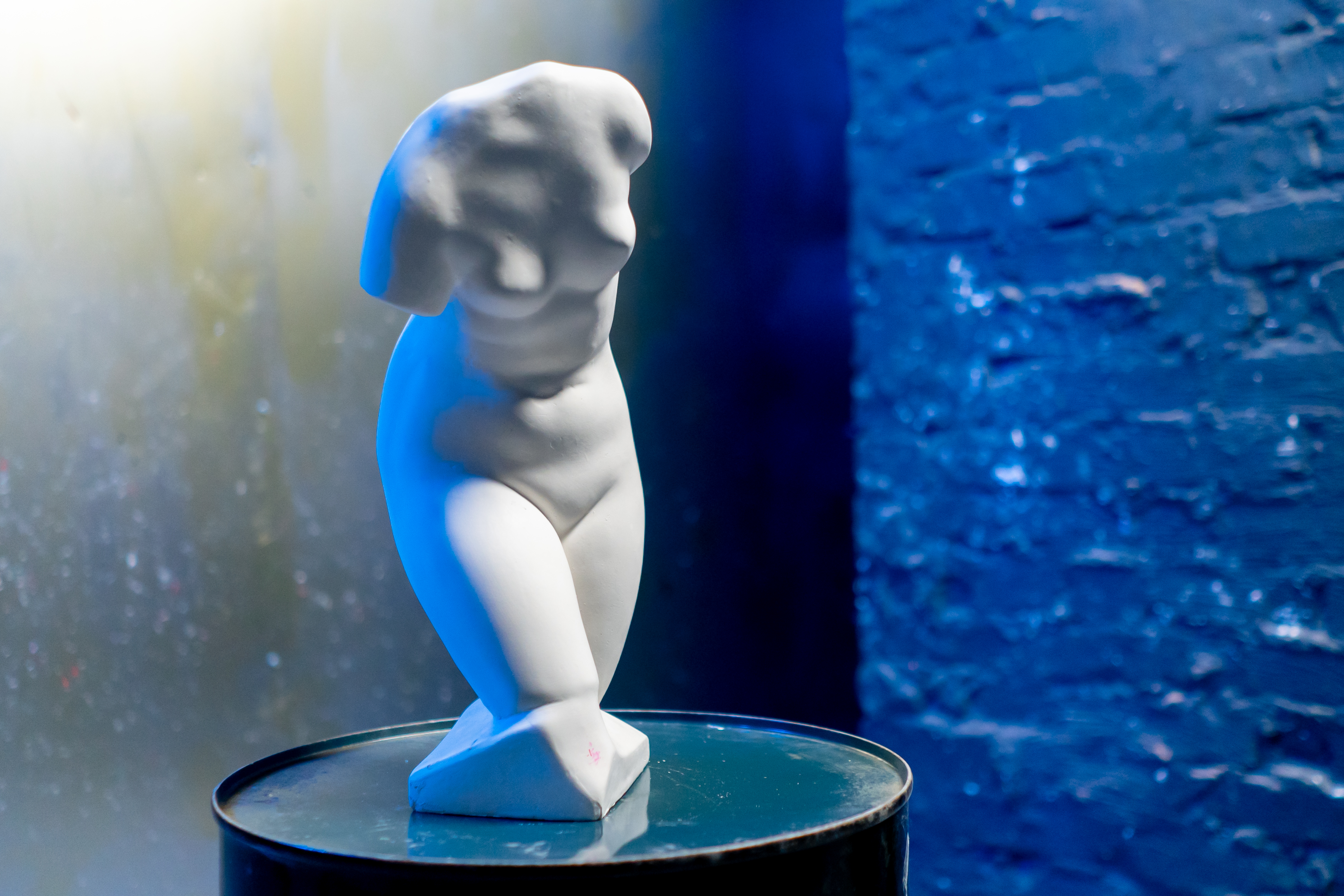 white sculpture of a torso on blue background